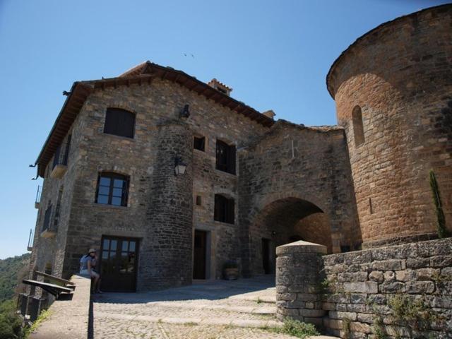 un grand bâtiment en briques avec une personne debout devant lui dans l'établissement El Mirador de Ainsa, à Aínsa