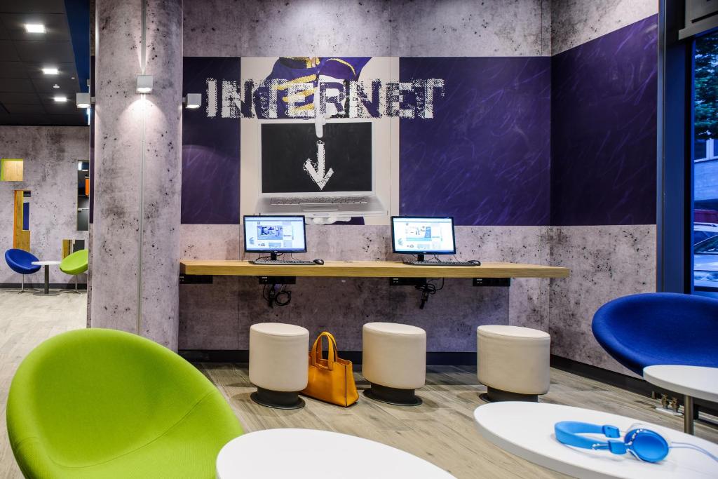 a waiting room with two computers on a table and chairs at Ibis Budget Salzburg Airport - Self-Check-In in Salzburg