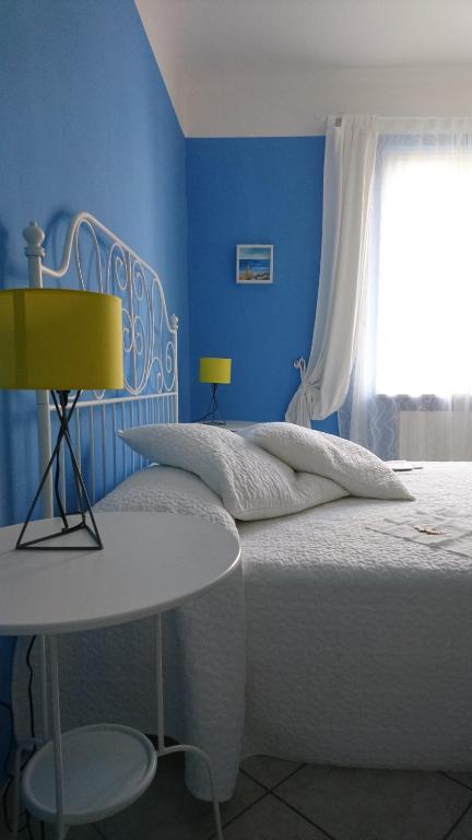 a blue bedroom with a white bed and a window at La Divina in Muggiano