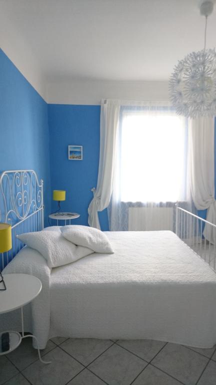 a blue bedroom with a white bed and a window at La Divina in Muggiano