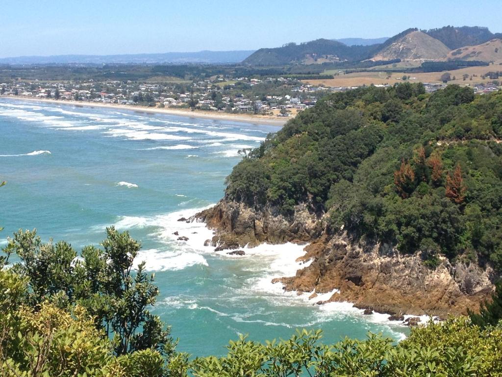 a view of the ocean with a beach and trees at Waihi Beach Getaway-Studio, Ensuite & Private Deck in Waihi Beach