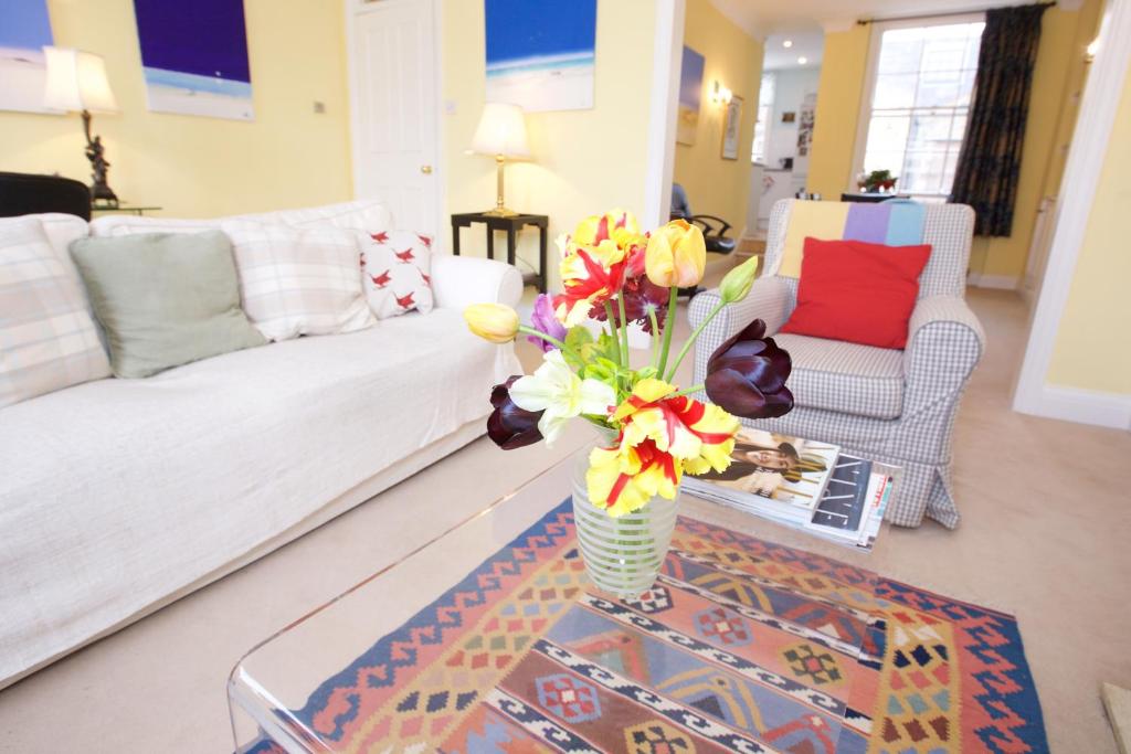 un soggiorno con un vaso di fiori su un tavolo di JOIVY Luxurious 2BR flat in Pimlico, near Warwick sq a Londra