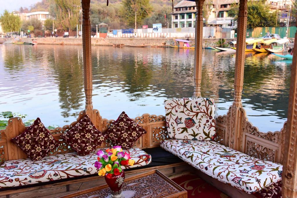 a boat with two chairs and a view of a river at White House Group Of Houseboats in Srinagar