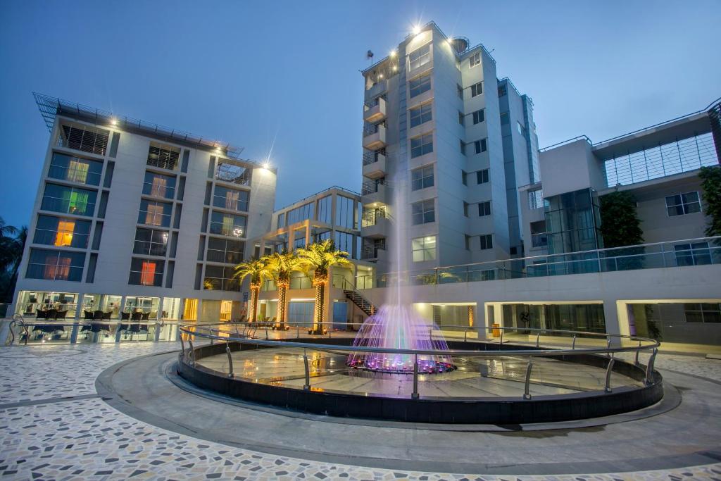 a fountain in the middle of a building with tall buildings at Momo Inn in Bogra