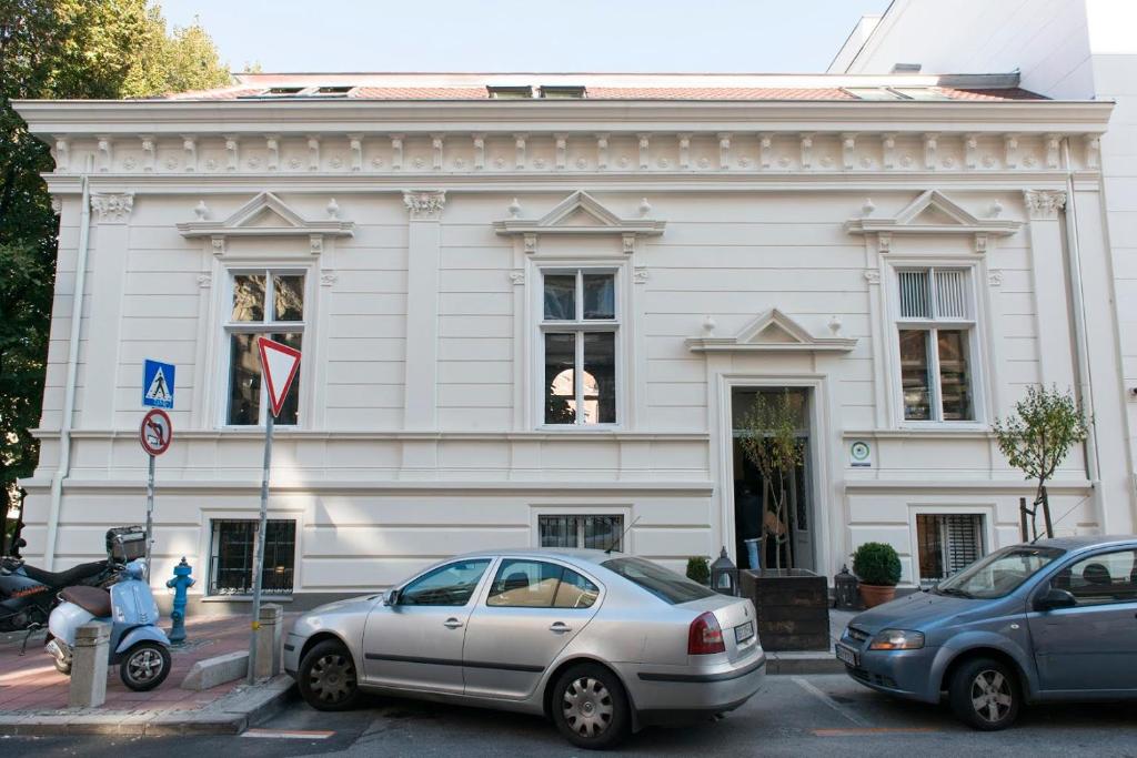 two cars parked in front of a white building at Smokvica Dorćol B&B in Belgrade