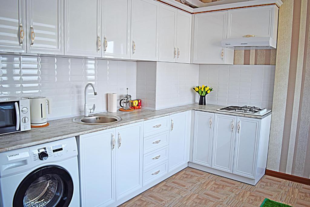 a kitchen with white cabinets and a washing machine at Apartment Kievskaya 114/2 in Bishkek