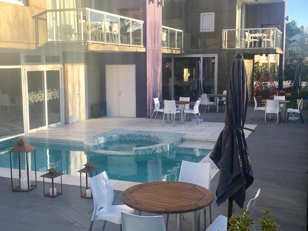 una piscina con mesa y sillas y un edificio en CÁFILA Apart & Spa en Las Gaviotas