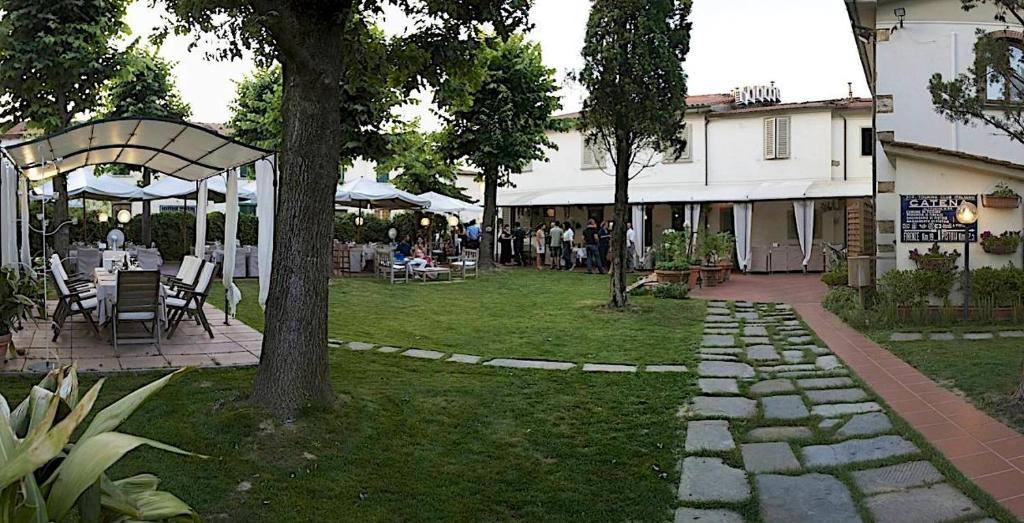 un jardín con mesa y sillas y un edificio en La Bussola Da Gino, en Quarrata