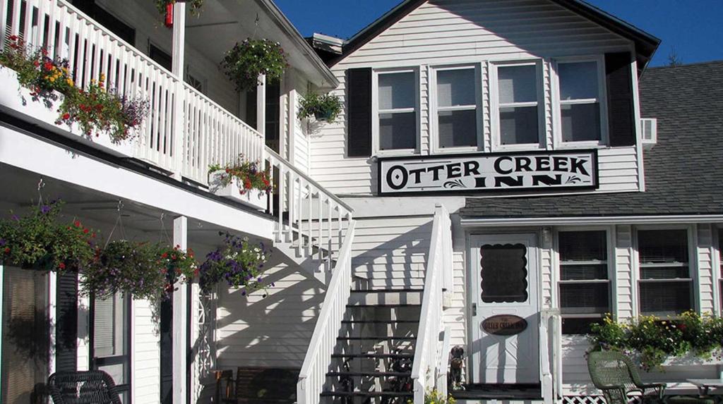 Otter Creek Inn في Otter Creek: مبنى أبيض عليه علامة عيادة الخور المعروضة