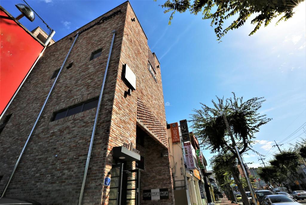 a tall brick building on a city street at Guest House Brick in Jeju