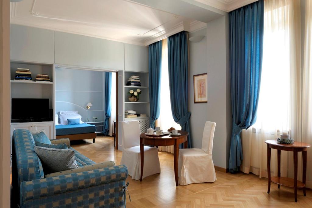 uma sala de estar com cortinas azuis e um sofá azul em Dea Suite Roma em Roma