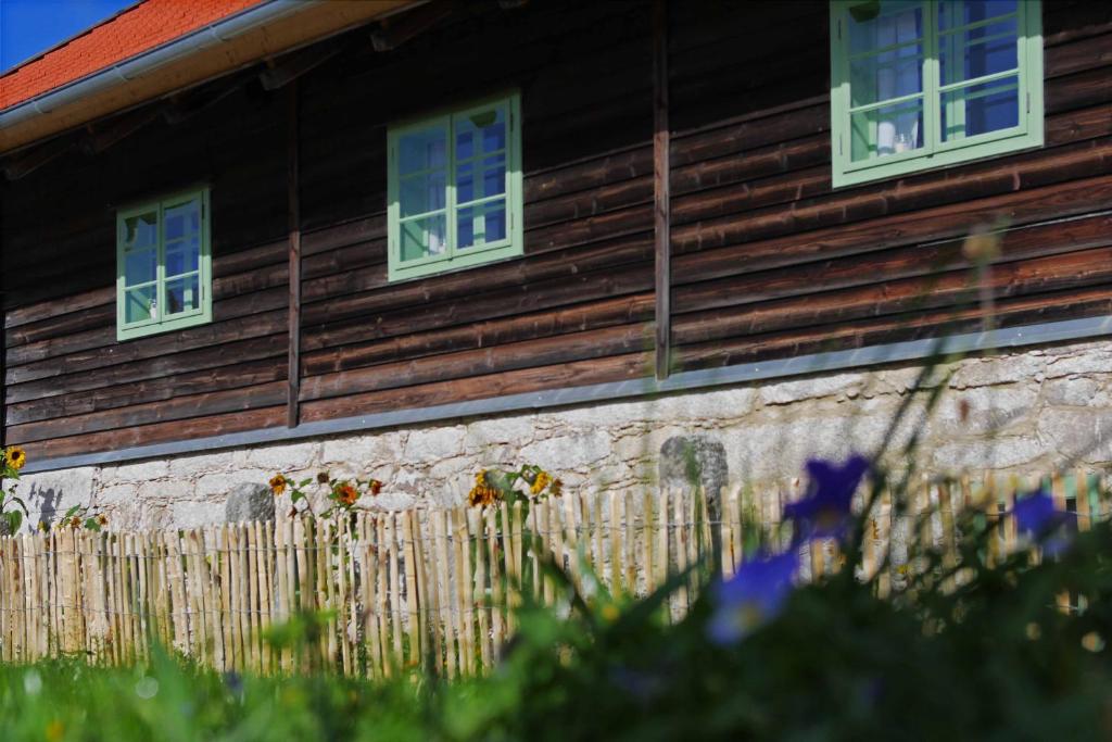 een houten huis met twee ramen en een hek bij Haidhäusl in Haidmühle