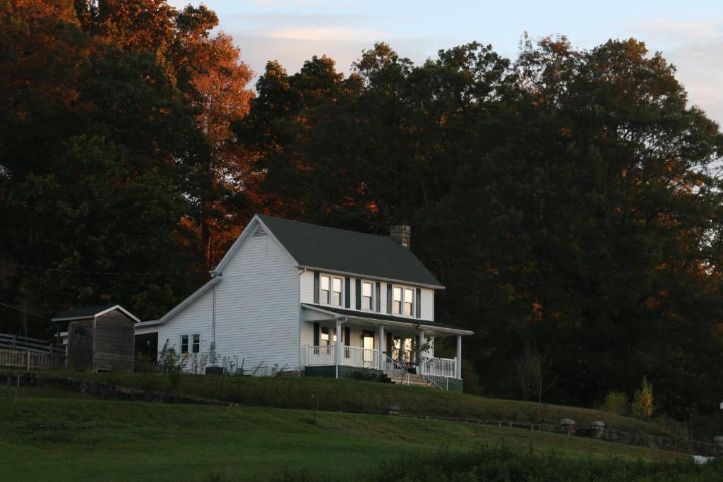 una casa blanca en una colina con árboles en Awesome Flat Top Farmhouse, en Ghent