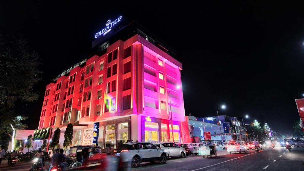 齋浦爾的住宿－齋浦爾金色鬱金香精華酒店，城市街道上一座红色的紫色灯光建筑