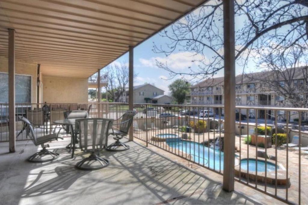 a covered deck with chairs and a swimming pool at Windrow Retreat in New Braunfels