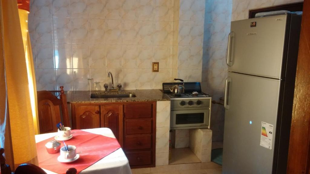 a kitchen with a white refrigerator and a table with a red at Apart Termal San Ramon in Termas de Río Hondo