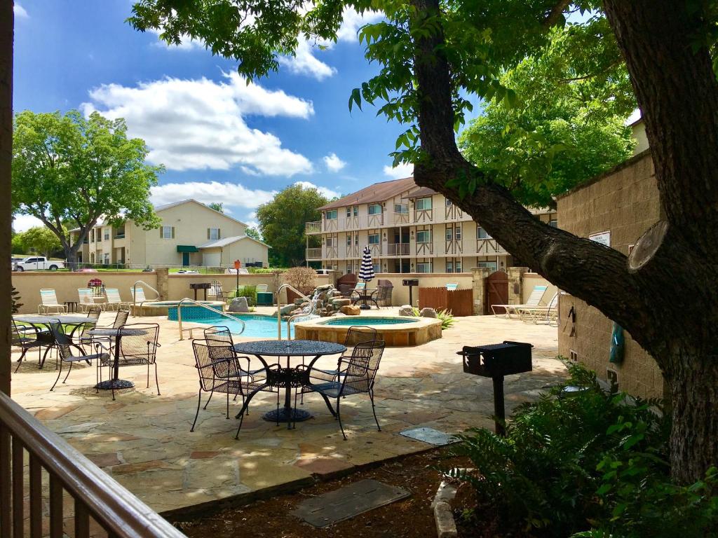 a patio with tables and chairs next to a pool at The Guadalupe Escape in New Braunfels