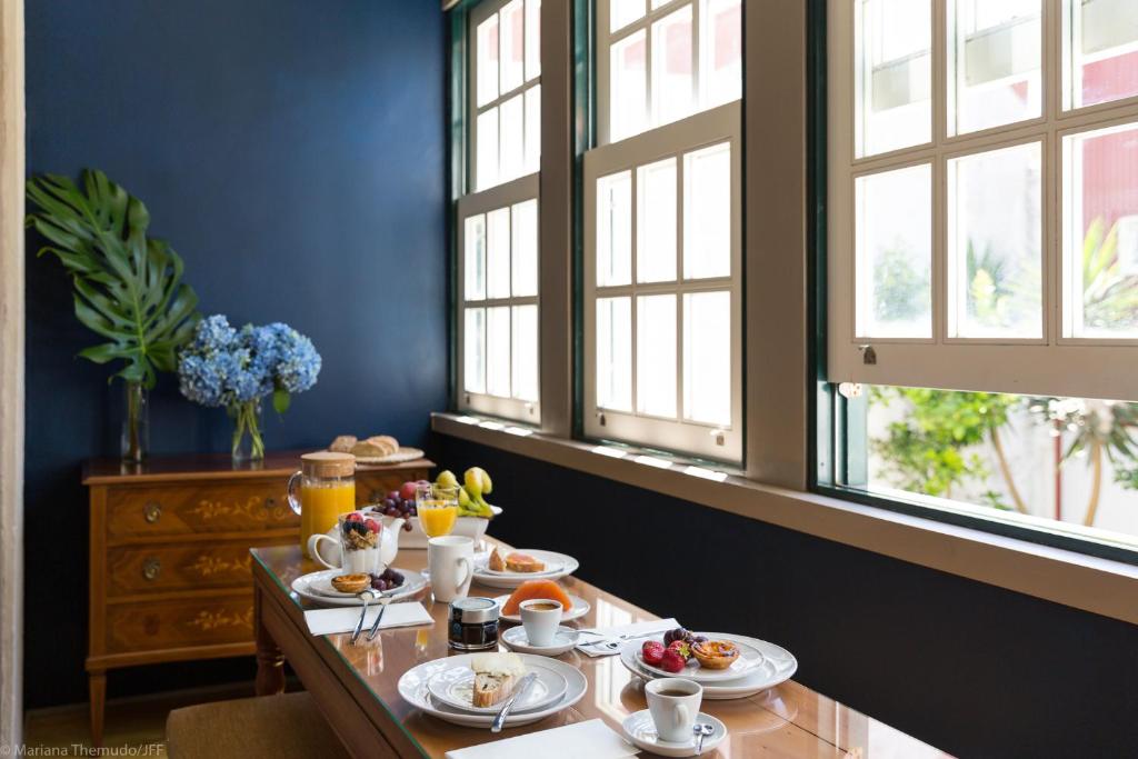 una mesa con platos de comida en una habitación con ventanas en Romantic - Casa Rua Bela, en Oporto