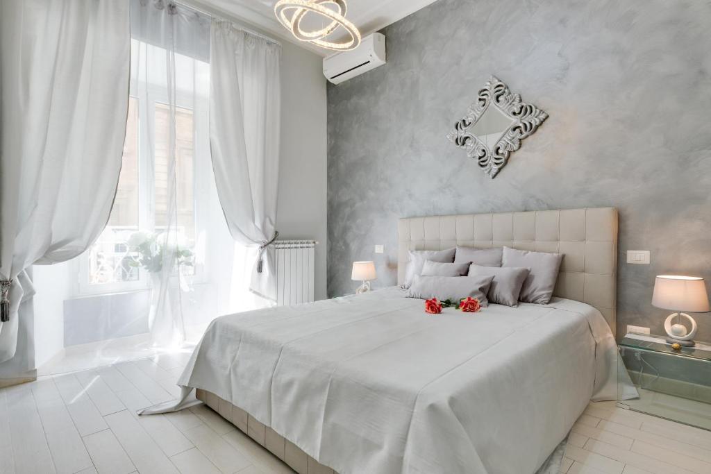 a white bedroom with a large bed with red flowers on it at Louise at Colosseum in Rome