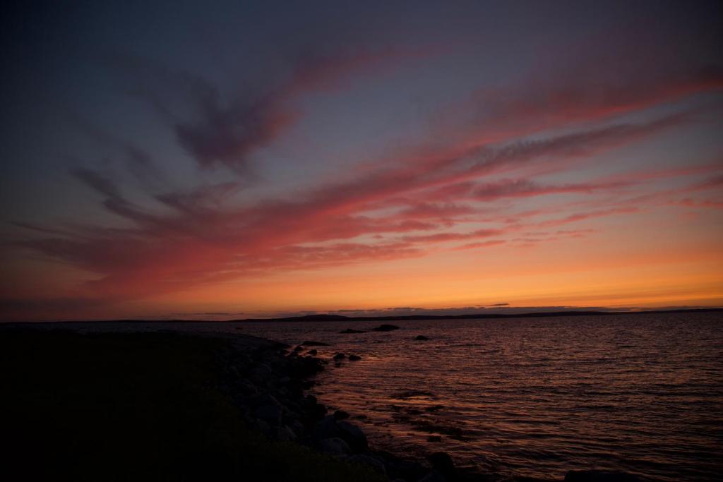zachód słońca nad oceanem z skalistym wybrzeżem w obiekcie Oyster Cottage w mieście Peggy's Cove