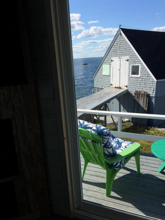 a green chair on a porch with a view of the ocean at Starfish Cottage in Peggy's Cove