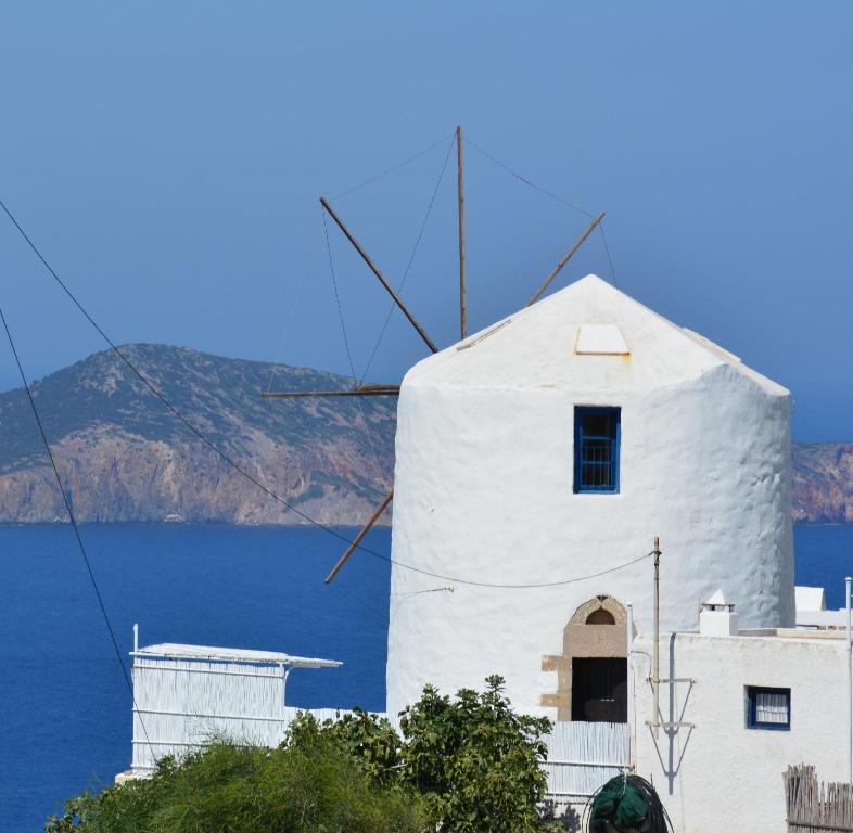 un moulin à vent devant une masse d'eau dans l'établissement Milos Vaos Windmill, à Plaka Milou
