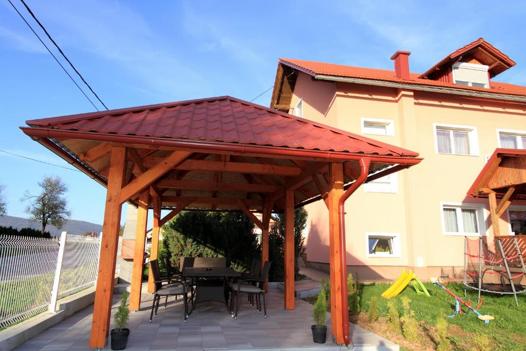 a wooden pavilion with a table and chairs on a patio at Guesthouse Viktorija Flat in Otočac