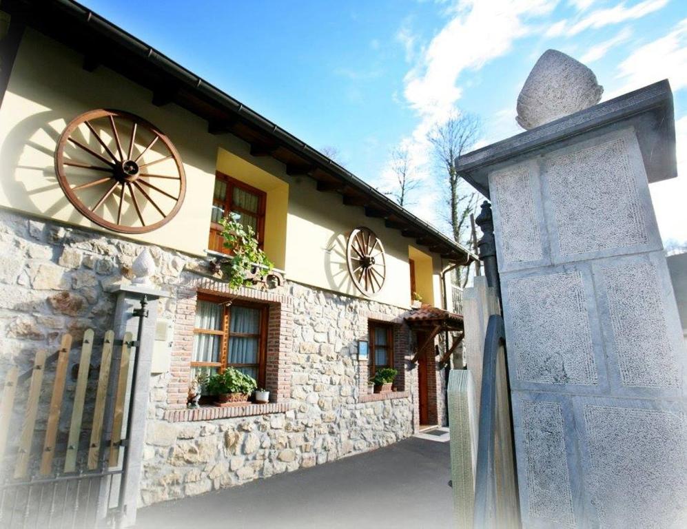 une maison en pierre avec une roue sur son côté dans l'établissement Apartamentos Rurales Villa-García, à Corigos