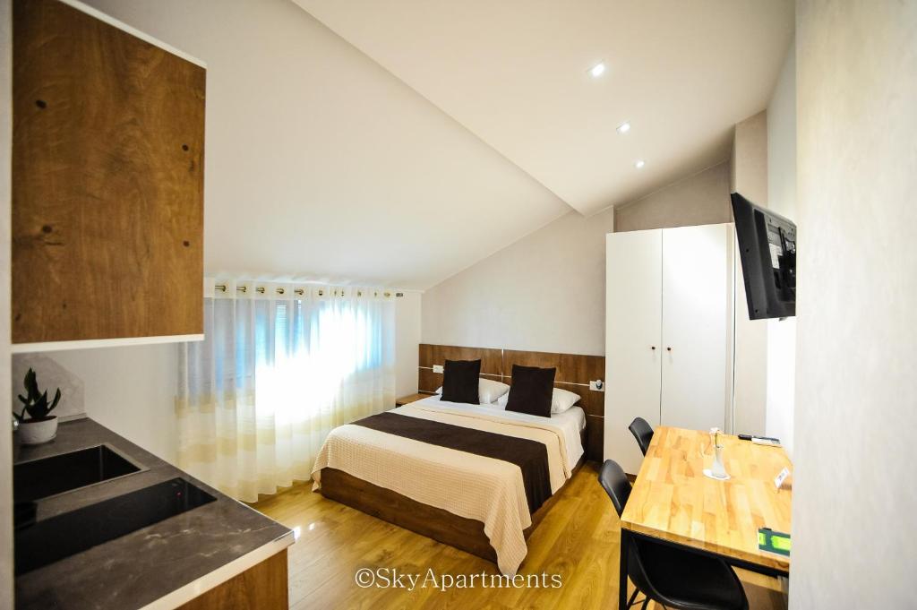 ein Schlafzimmer mit einem Bett und eine Küche mit einem TV in der Unterkunft Sky Apartments in Tirana