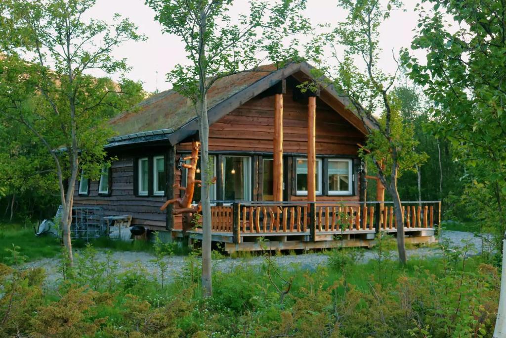 ein Blockhaus mit einer großen Terrasse im Wald in der Unterkunft Cabin by the river in Storslett