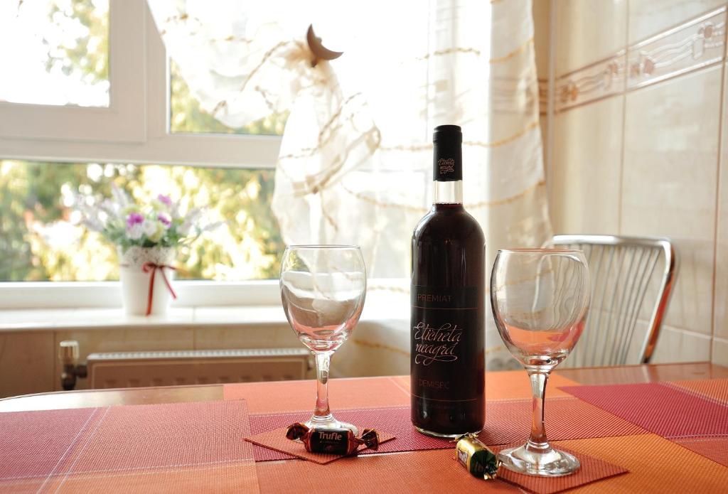 una bottiglia di vino seduta su un tavolo con due bicchieri di Stephanie Apartment a Braşov