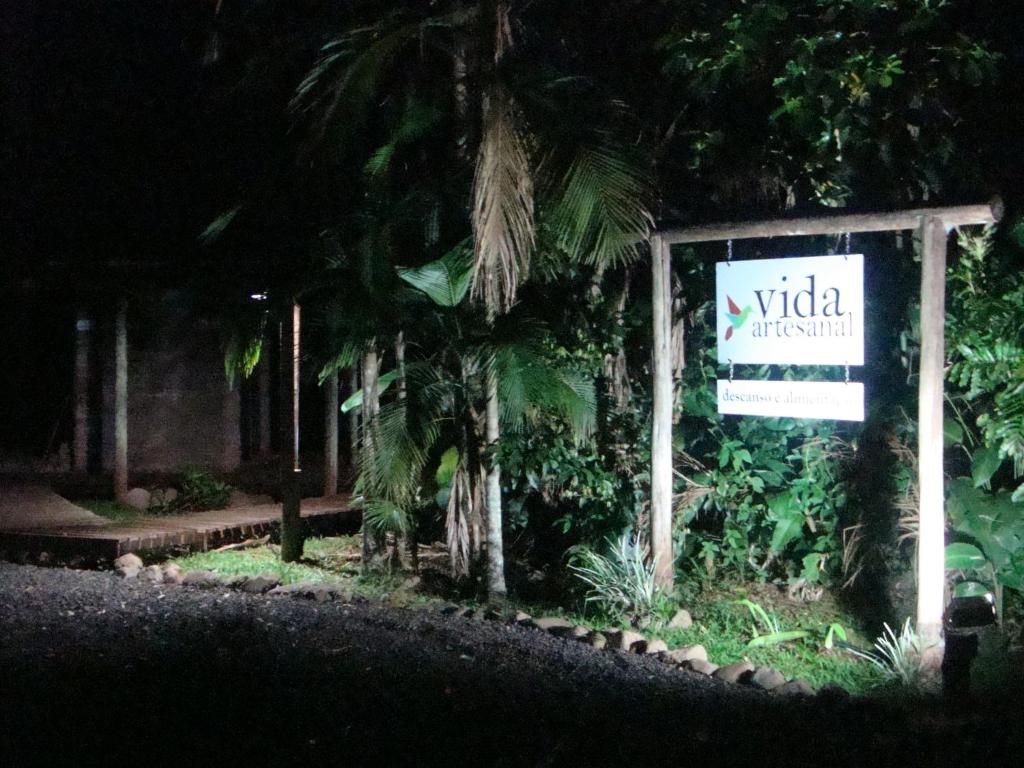 a sign in front of a hotel at night at Pousada Vida Artesanal in Pedra