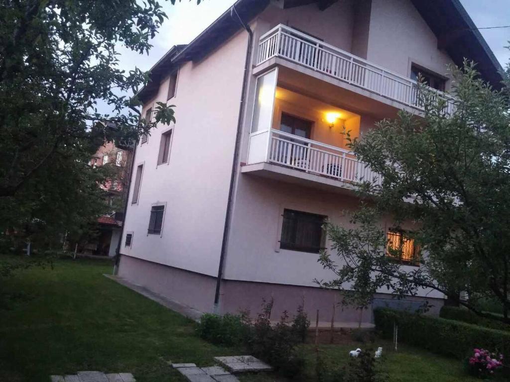 a large white building with a balcony and a yard at Apartman "Beban" in Sarajevo