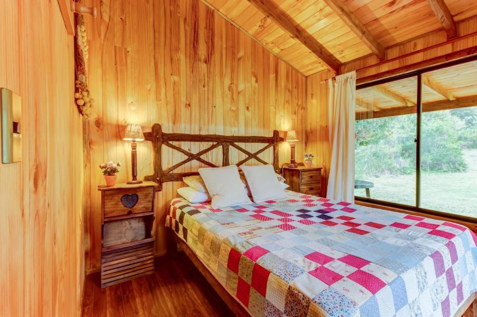 a bedroom with a bed in a wooden room at Murmullo de Arroyos in Caburgua
