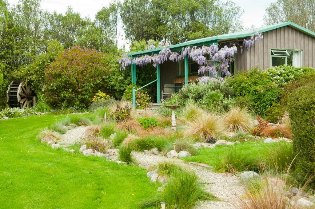 un jardín con una casa con flores púrpuras en Waterwheel Cottage, en Upper Moutere
