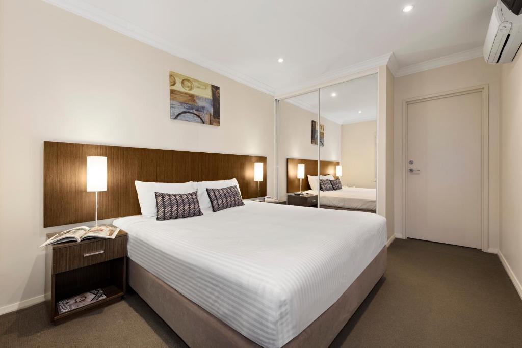a bedroom with a large white bed and a mirror at Quest Singleton in Singleton