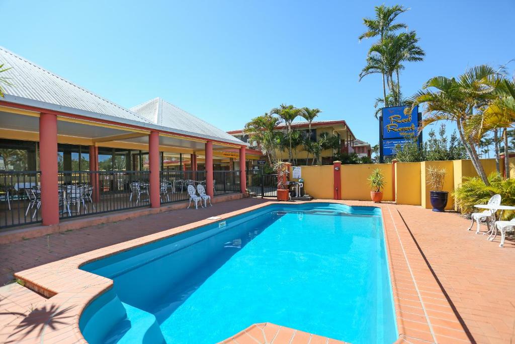 a swimming pool in front of a house at Reef Resort Motel in Mackay