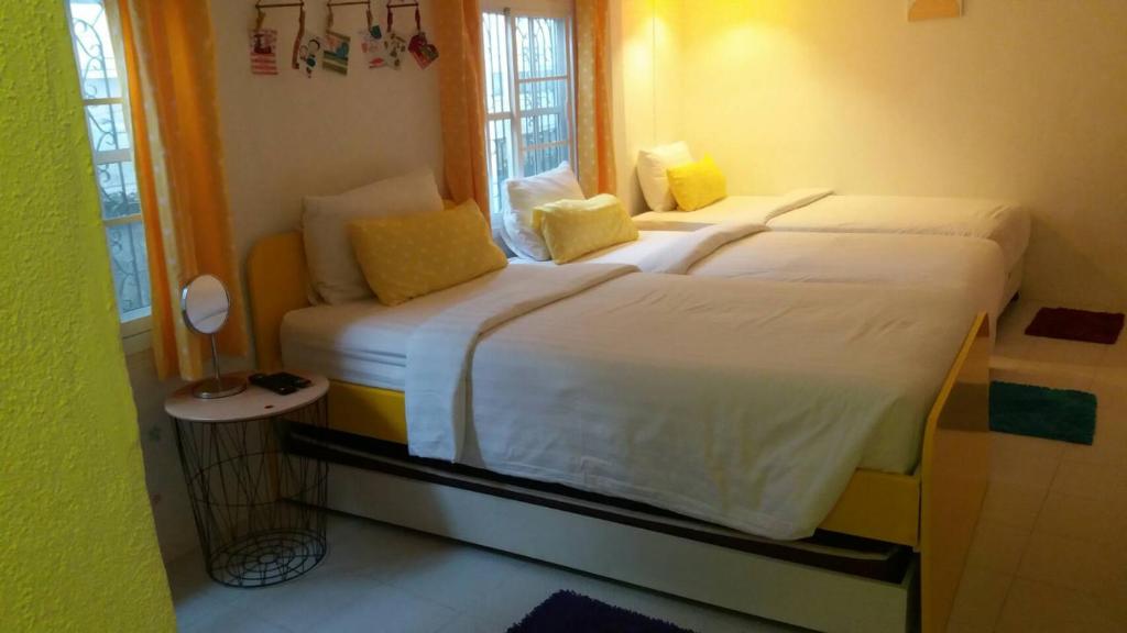 a bedroom with a large white bed with yellow pillows at Na-Rak-O Resort in Chiang Rai