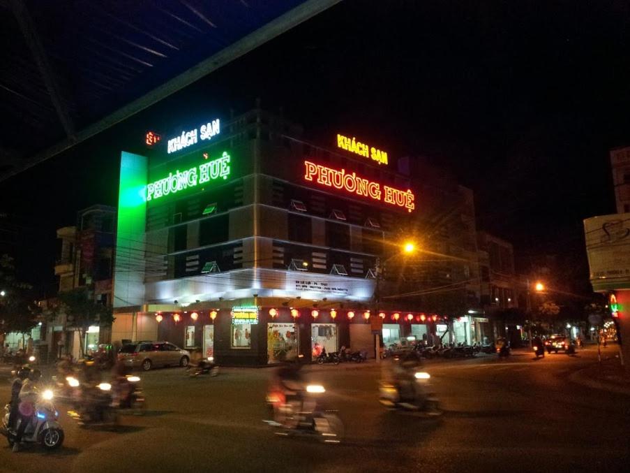 un edificio con letreros de neón en una calle por la noche en Phuong Hue Hotel en Soc Trang
