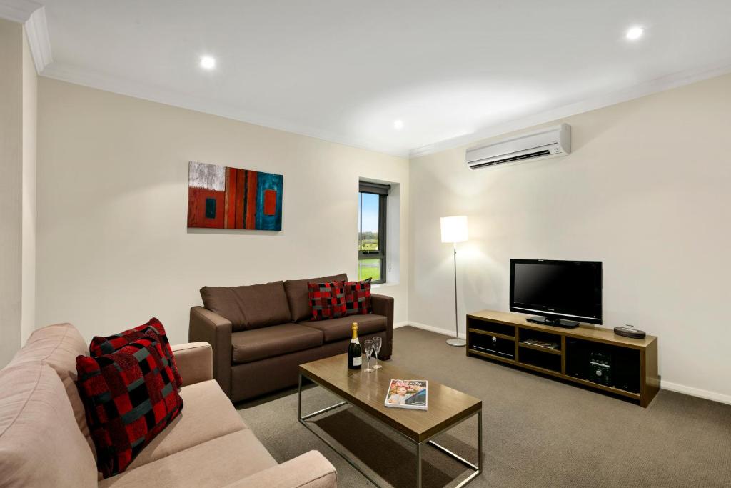 a living room with a couch and a flat screen tv at Quest Singleton in Singleton