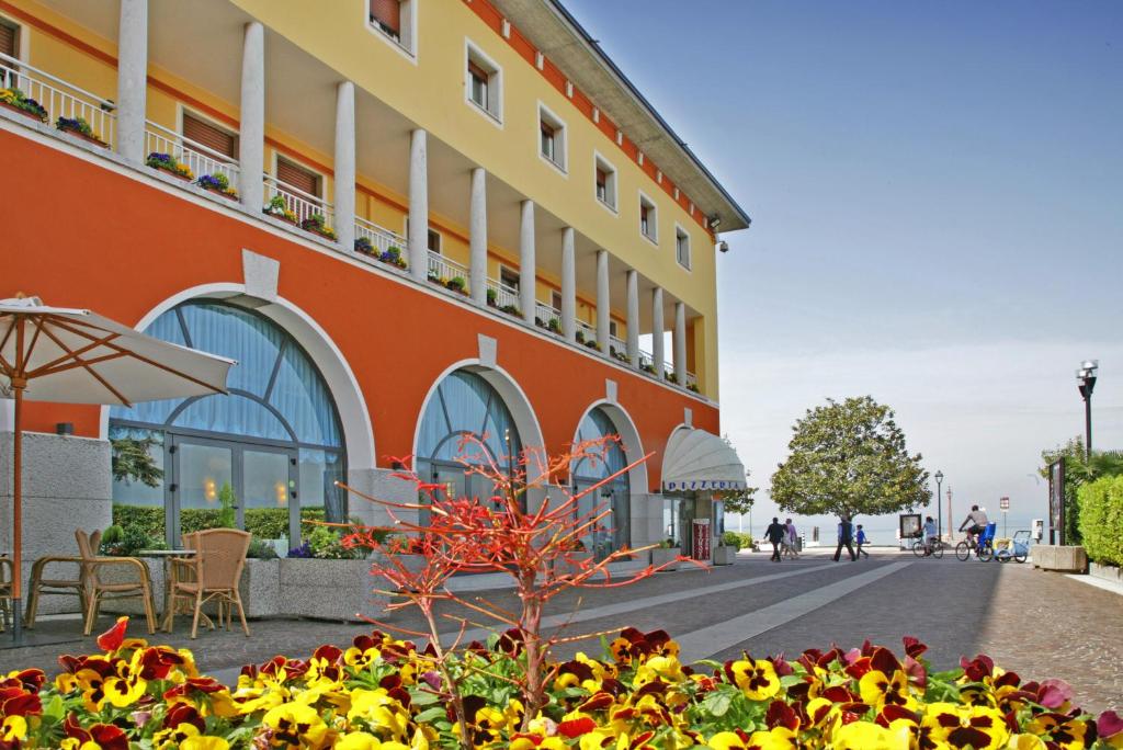 un bâtiment avec des fleurs devant lui dans l'établissement Hotel Vela D'oro ***S, à Bardolino