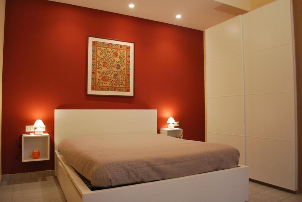 a bedroom with red walls and a bed with two lamps at Martihouse in Cagliari