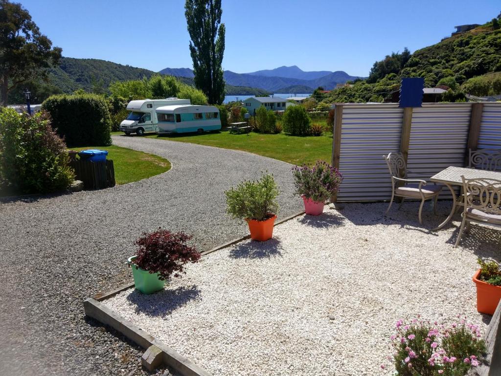 a patio with potted plants and a table and a trailer at Picton's Waikawa Bay Holiday Park in Picton
