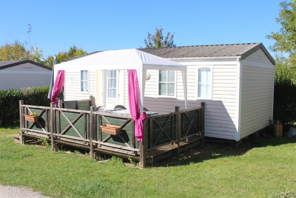 a small white house with a porch and a fence at Camping du Pontis in Verteillac