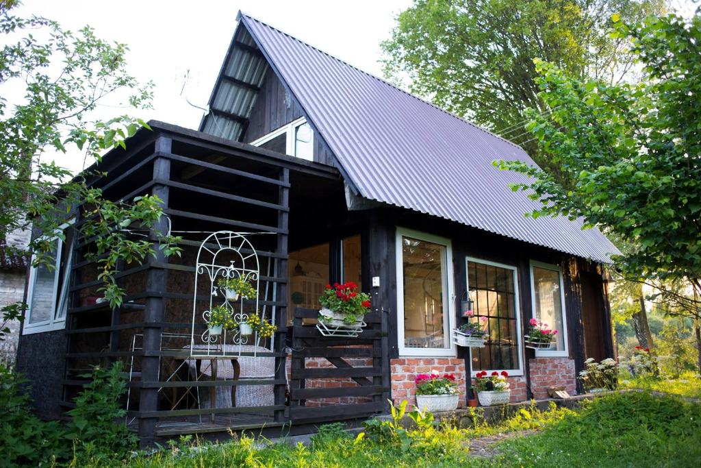 Wiejski Dom في Resko: منزل صغير بسقف أسود ونوافذ