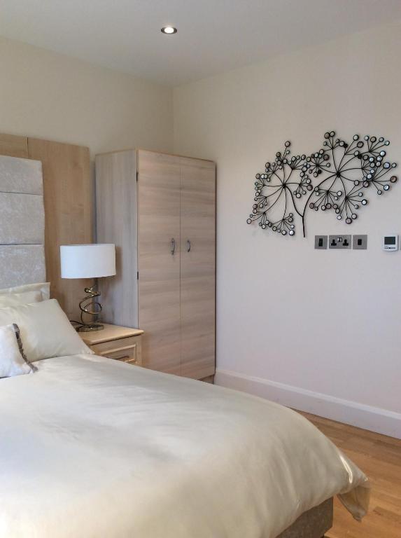 a bedroom with a large white bed and a cabinet at Modern Flat in Watford