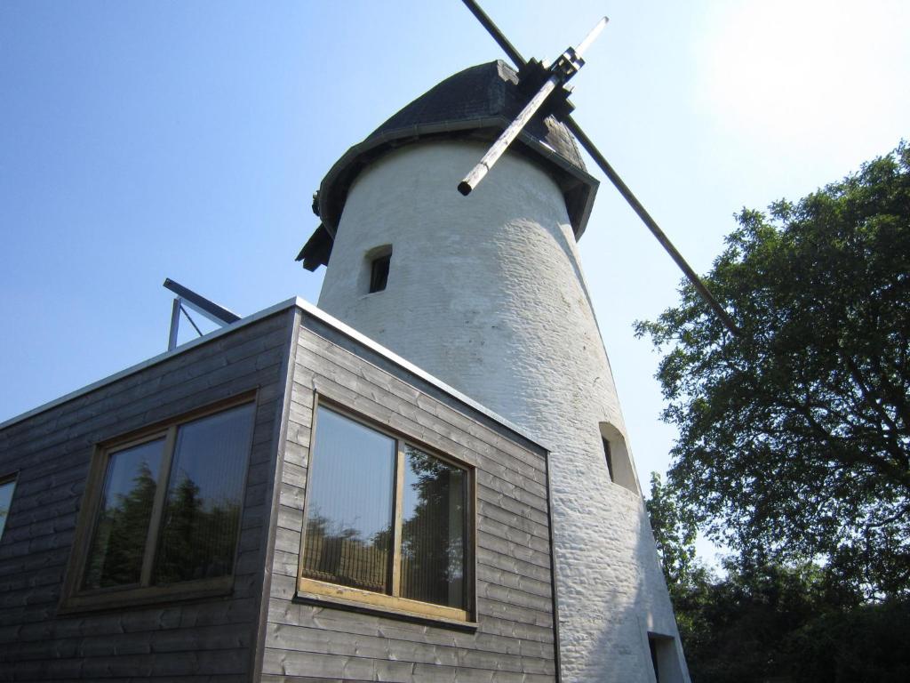 a building with a windmill on top of it at home in the Flemish Ardennes between the meadows in Sint-Kornelis-Horebeke