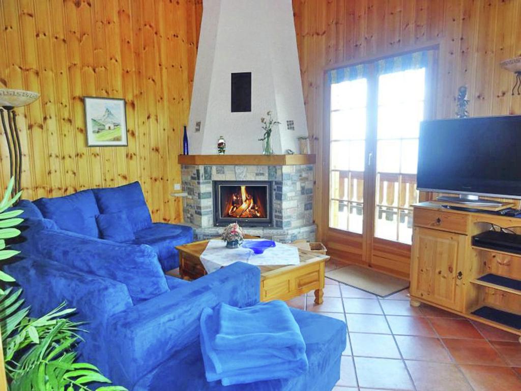 a living room with a blue couch and a fireplace at Comfortable Holiday Home with Fireplace in Vex in Les Collons