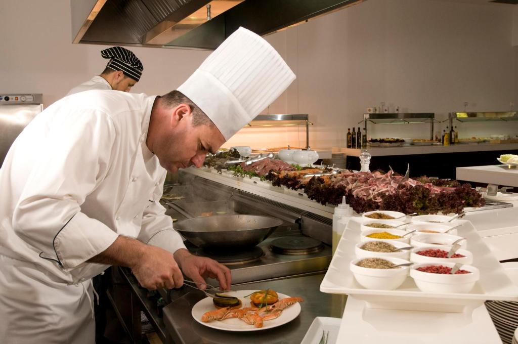 a chef preparing a plate of food in a kitchen at Las Gaviotas Suites Hotel & Spa in Playa de Muro