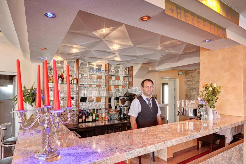 a man standing behind a bar in a restaurant at Hotel zum Ochsen in Bietigheim